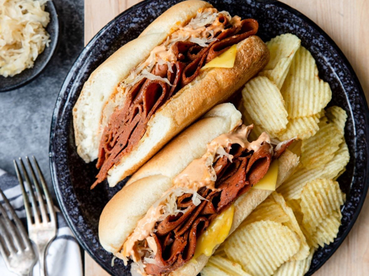 Unreal Deli plant-based Reuben sub served with chips