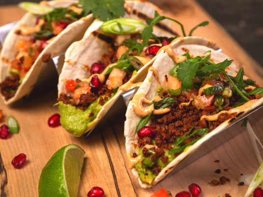 Taco shells filled with Very Good Taco Stuff’er, pomegranate seeds, avocado, cilantro and orange sauce